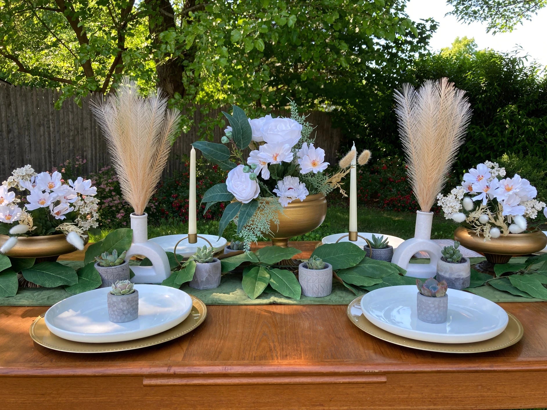 7 succulents displayed on a wedding table with gold place settings, white roses, candles, and decorative fronds.